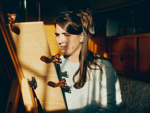 Woman painting inside yacht with shadows