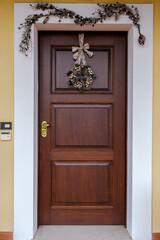 December 2020 - Milan: Christmas wreath hanging on a wooden door