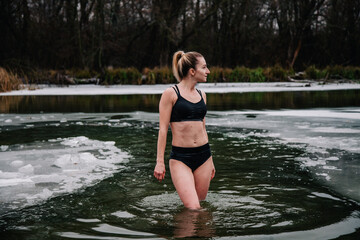 Fototapeta premium Young slender girl bathes in winter in a river hole
