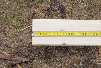 Building material, the board is measured with a tape measure, yellow, horizontal frame.