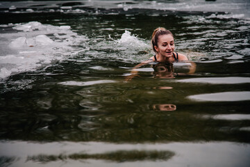 Fototapeta na wymiar Young slender girl bathes in winter in a river hole