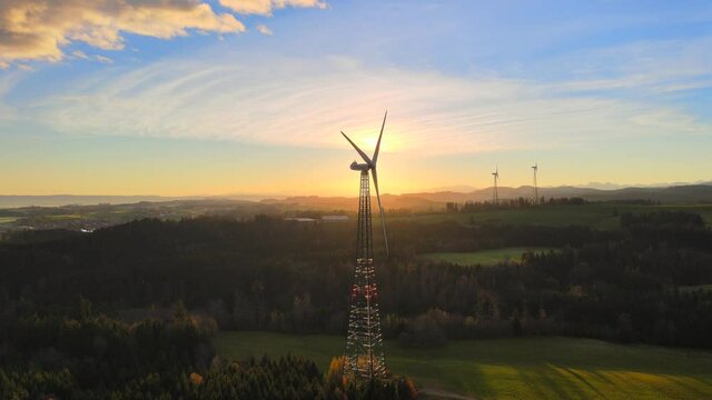 Drone shot rotating around wind turbine at sunrise