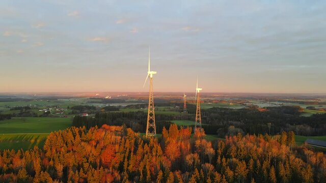 Drone shot rotating around three wind turbines at sunrise