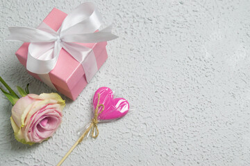gift box with flowers and lollipop on top on pink valentine's day background. Copyspace.