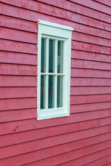 The exterior of a vintage redwood building. The wall is covered in narrow wooden clapboard. The...