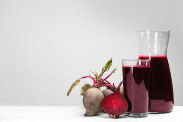 Fresh beet juice and raw vegetable on white wooden table. Space for text