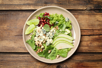 Fresh salad with pear on wooden table, top view