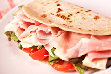 Traditional Italian piadina with ham, cheese, tomato and salad.