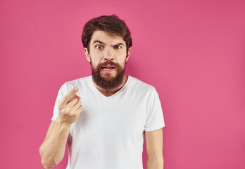 Irritated male gesturing with his hands on a pink background cropped view