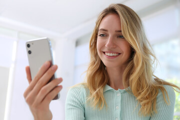 Young woman unlocking smartphone with facial scanner indoors. Biometric verification