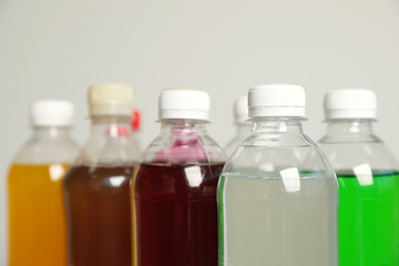 Bottles of soft drinks on grey background, closeup