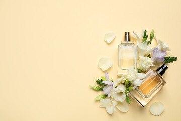 Flat lay composition with different perfume bottles and freesia flowers on yellow background, space for text