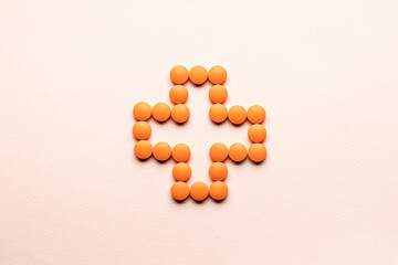 pill cross shape isolated over pastel pink background. creative minimal. studio shot. above view. pharmacy concept