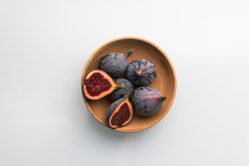 Figs in a small wooden bowl in white background