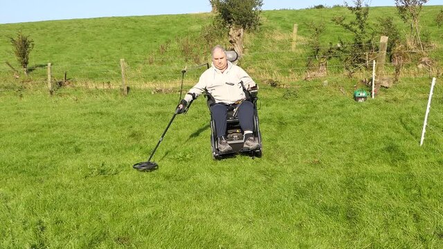 Disabled Wheelchair user metal detecting in a field
