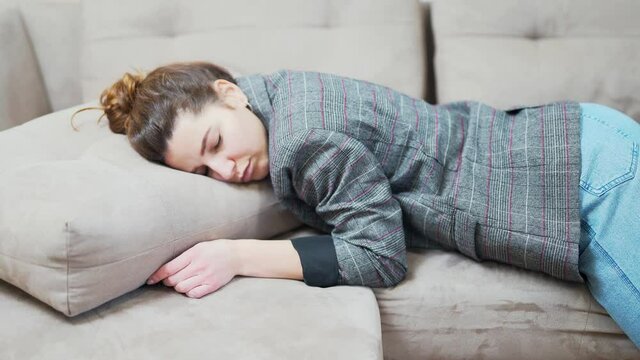 Exhausted young woman falls on the couch after work. Sleepy without strength Adult girl after a hard day's work goes to bed at home on the sofa. Time out. student or business woman