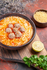 Tasty meatballs soup with noodles on board lemon wooden pasta a bunch of greens on dark table footage