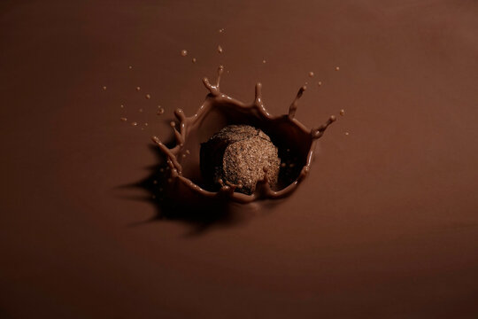 delicious chocolate truffle covered with muscovado sugar splashing into chocolate milk