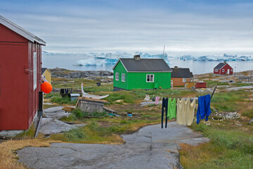 Colorful houses, drying fish, and sled dogs are a common sight in Rodebay (Oqatsut), set on the...