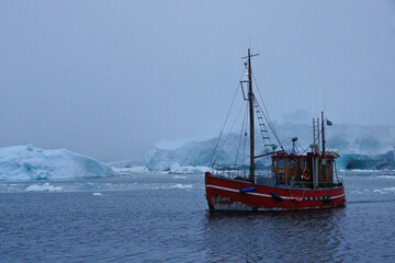Fishing boat among icebergs in foggy Disko Bay, Ilulissat, Greenland
