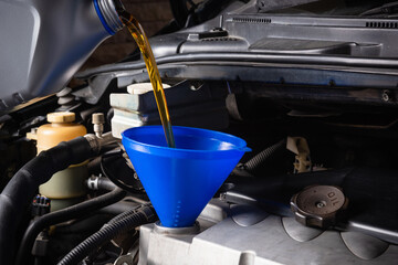 Mechanic in service to repair the car, refueling and pouring from bottle to change lubricant oil at...