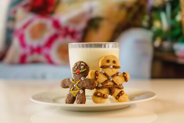 BDSM themed gingerbread cookies. fun looking cookies and a glass of milk. Sexy cookie with mouth ball and leather suit look designed in bsdm style.