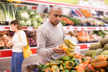 Portrait of man in produce section of supermarket choosing sweet paper and bananas