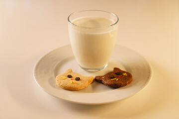 Cocoa and gingerbread cookies for New Year's Eve and Christmas themed. An image of a cat-like cookie and a glass of milk with a Christmas tree and fireplace in the background.