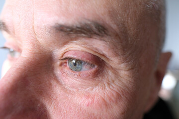 serious elderly man, face with wrinkles, green eyes close up, concept of human memory training, emotions, age problems