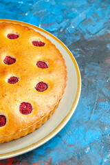 front half view raspberry cake on oval plate on blue table