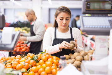 Woman working in supermarket near fruit section