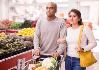 Beautiful latin couple choosing fruits in supermarket together