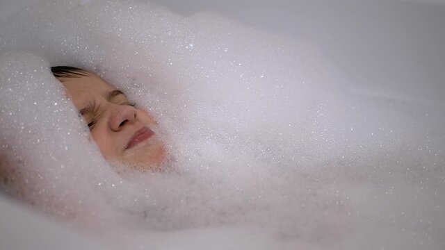 Face of Smiling Little Boy Lying in a Bubble Bath. Relaxation in Water. Close-Up