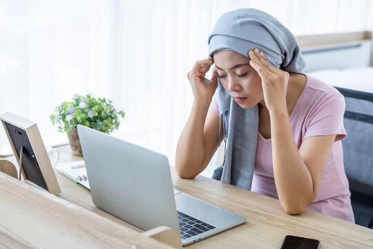 Stressed of a asian women disease mammary cancer patient Have a headaches stick pink ribbon wearing headscarf After treatment to chemotherapy with working business at laptop in office at home