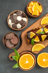 Soft cakes on wooden cutting board and cut lemons with leaves biscuits on dark background