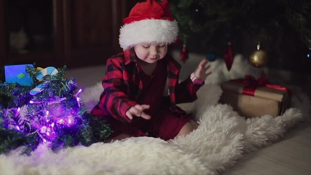 a child in red clothes is sitting waiting for the new year. the concept of celebrating Christmas at midnight. holiday costume