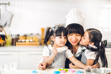 Portrait of enjoy happy love asian family mother and little asian girl daughter child having fun cooking together with baking cookies and cake ingredients on table in kitchen