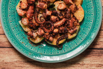 Turquoise plate with Galician octopus on a wooden table. Concept healty food.