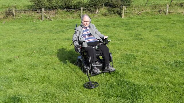 Disabled Wheelchair user metal detecting in a field