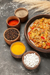 bottom view roasted aubergine salad in bowl different spices in small bowls on dark background