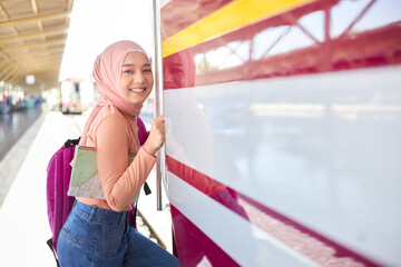 Asian Muslim woman stepping into the public train to commute.