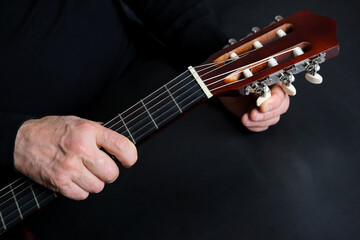 guitarist tunes instrument, man plays the guitar, close-up hands, the concept of creativity, learning to play musical instruments, online learning