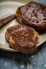 Slice of homemade bread with chocolate cream on the kitchen table for breakfast. Selective focus. Shallow depth of field.
