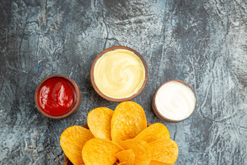 Half shot of tasty potato chips decorated like flower shaped and salt with ketchup mayonnaise on gray background