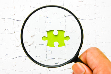 A picture of copyspace jigsaw with copyspace green background and magnifying glass insight.