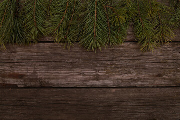 Christmas pine tree branches on old rustic wooden desk background. Xmas or New Year celebration concept. Top view, copy space, border, template for greeting cards and postcards