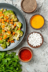 Horizontal view of healthy vegetable salad different spices and a bunch of green on white table