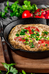  Homemade omelet with tomatoes and herbs in a pan on the table close up vertical photo