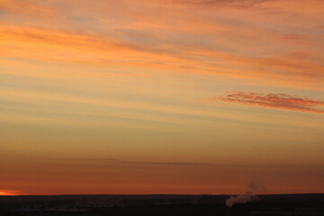 Sun below the horizon and clouds in the fiery dramatic orange sky at sunset or dawn backlit by the sun. Place for text and design