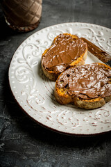 Slice of homemade bread with chocolate cream on the kitchen table for breakfast. Selective focus. Shallow depth of field.